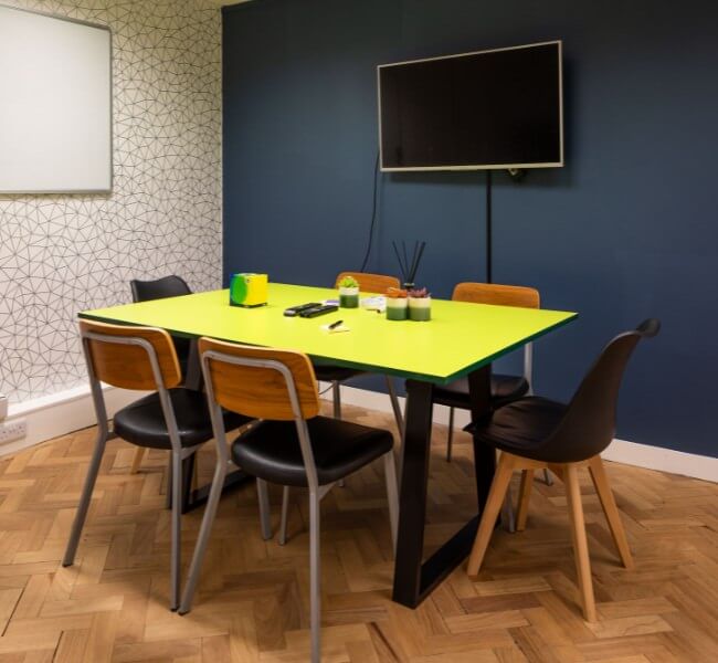 Meeting room in woking with a table, chairs and screen with accessories on the table