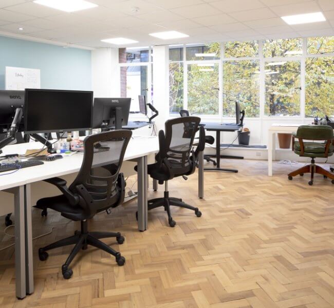 Serviced office in woking with five desks, chairs and screens for business use with a fishbone wooden floor