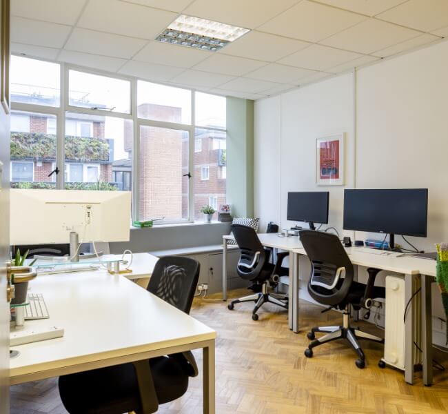 Serviced office in woking with multiple desks, chairs and screens for business use overlooking a large window