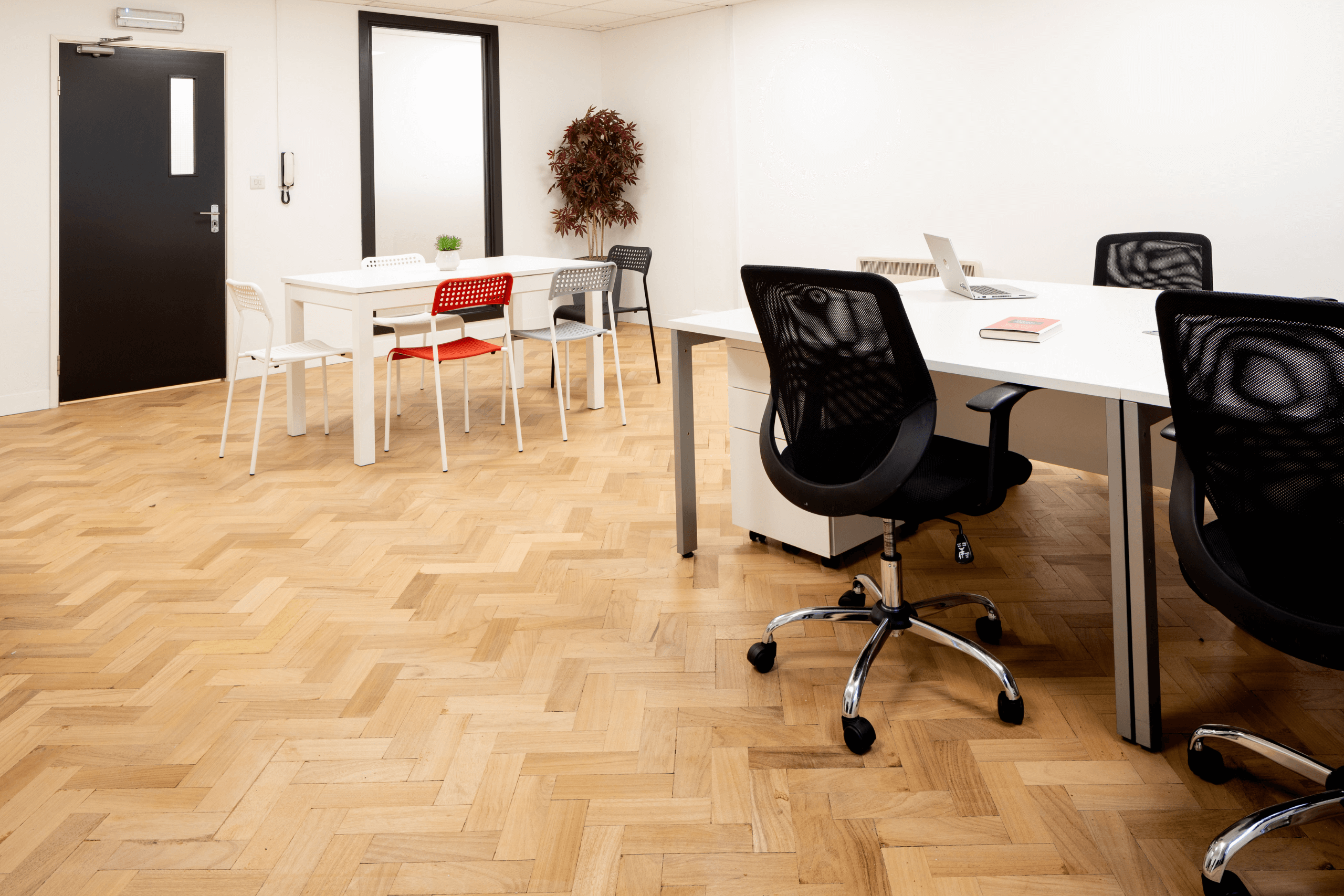 An office room with a row of desks and chairs, as well as a table and chairs.