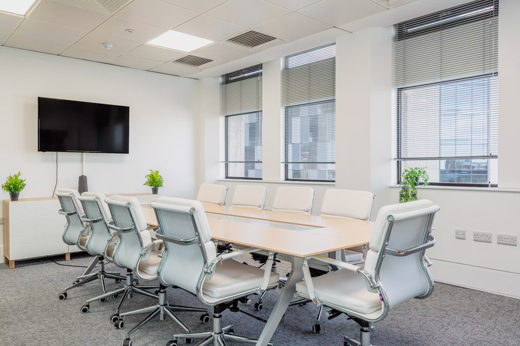 Modern meeting room in Woking with 8 chairs, white minimalist design, and wall-mounted TV