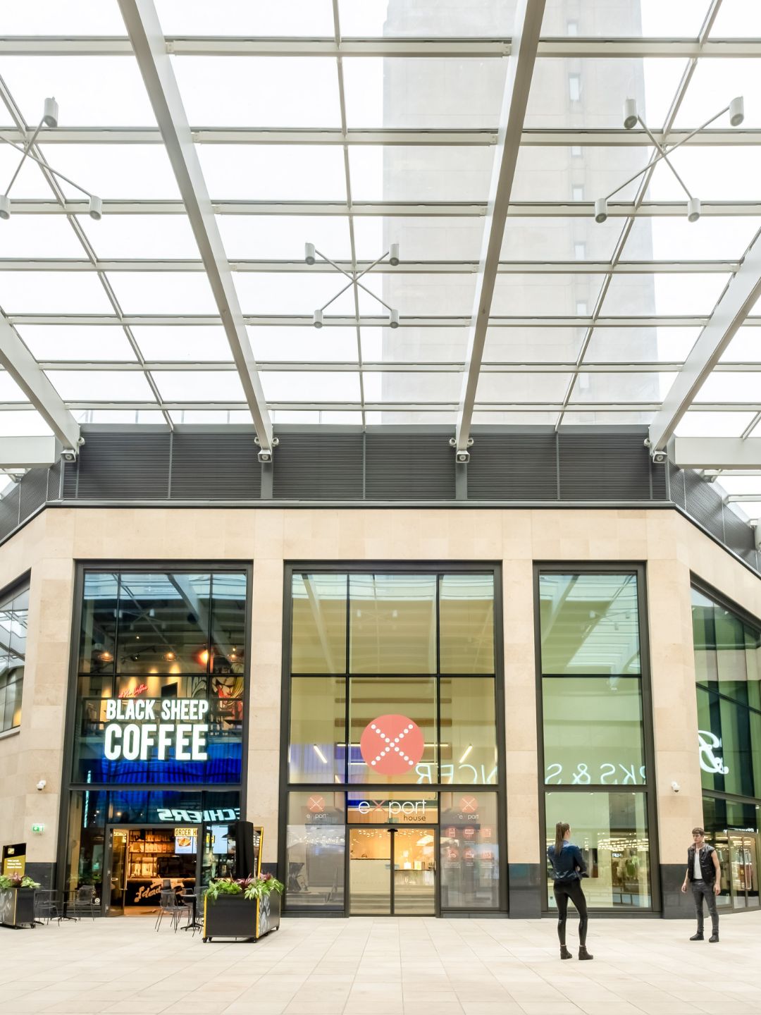 Entrance to Export House in Woking, modern building, glass doors to reception area and next to a coffee shop.
