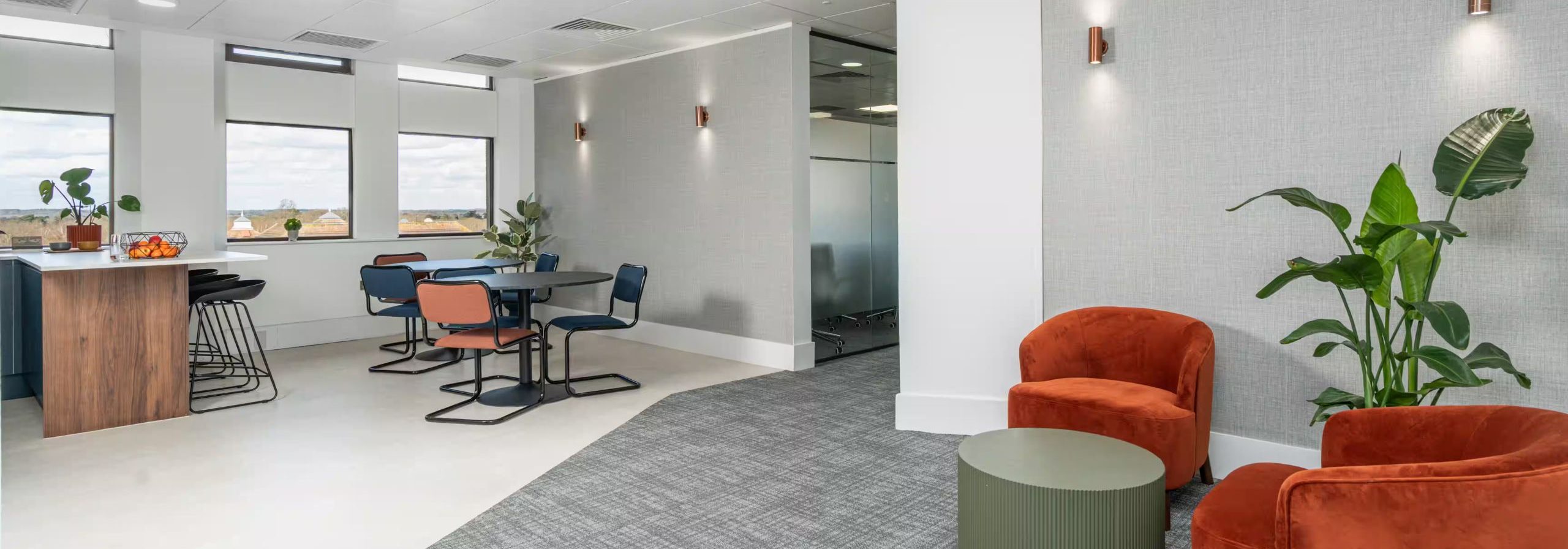 Office kitchenette with chairs, table, and corridor.