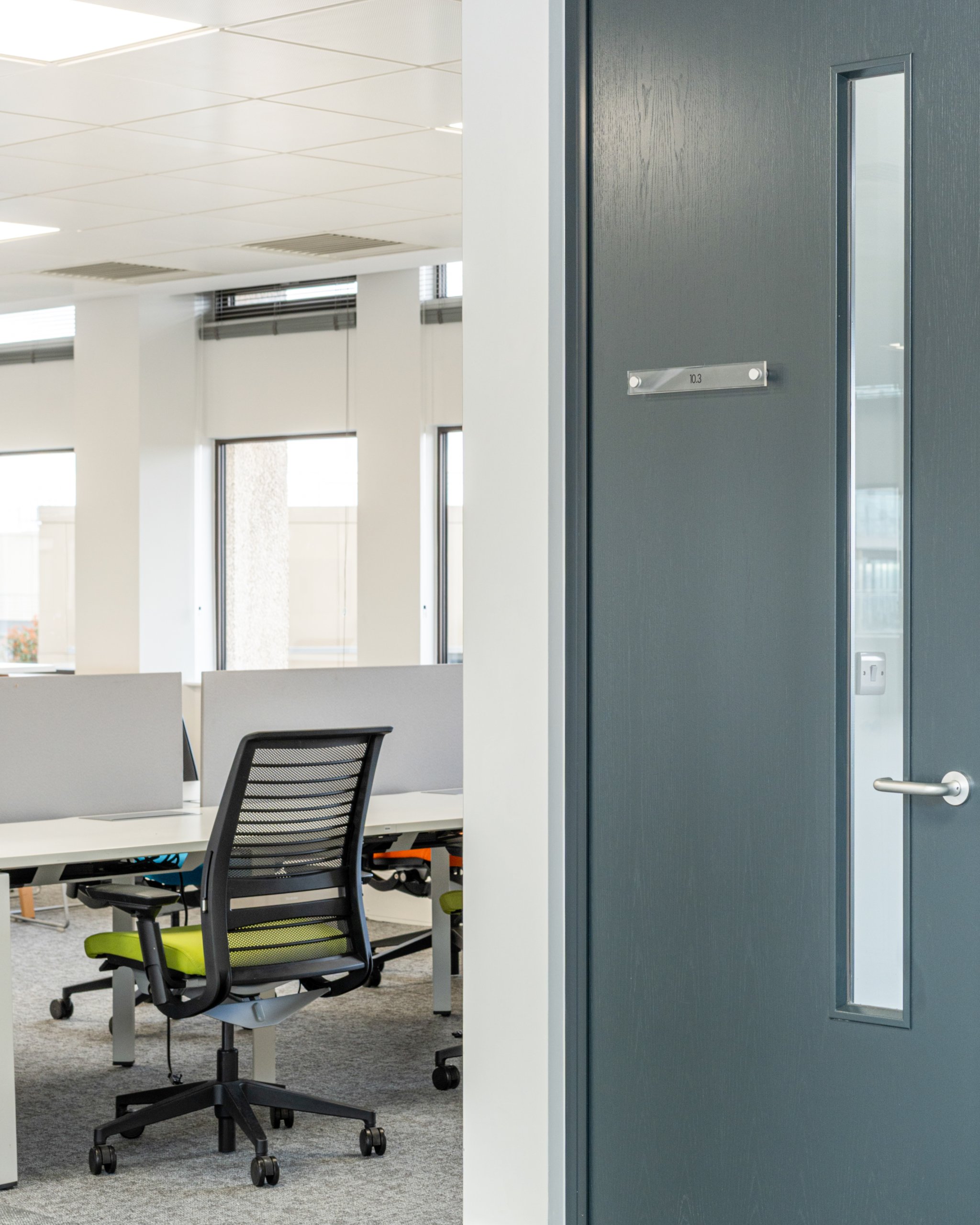 Office door open to a large workspace with a desk and office chair.